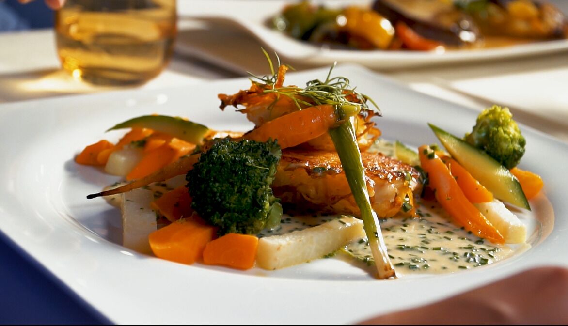 Ein Teller mit Lachs, Gemüse und Soße.
