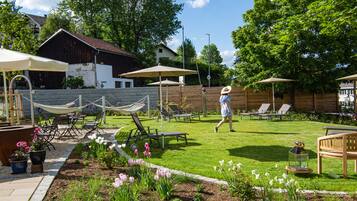 Relax in a serene outdoor space with lounge chairs, a hammock, and a garden surrounded by a fence.