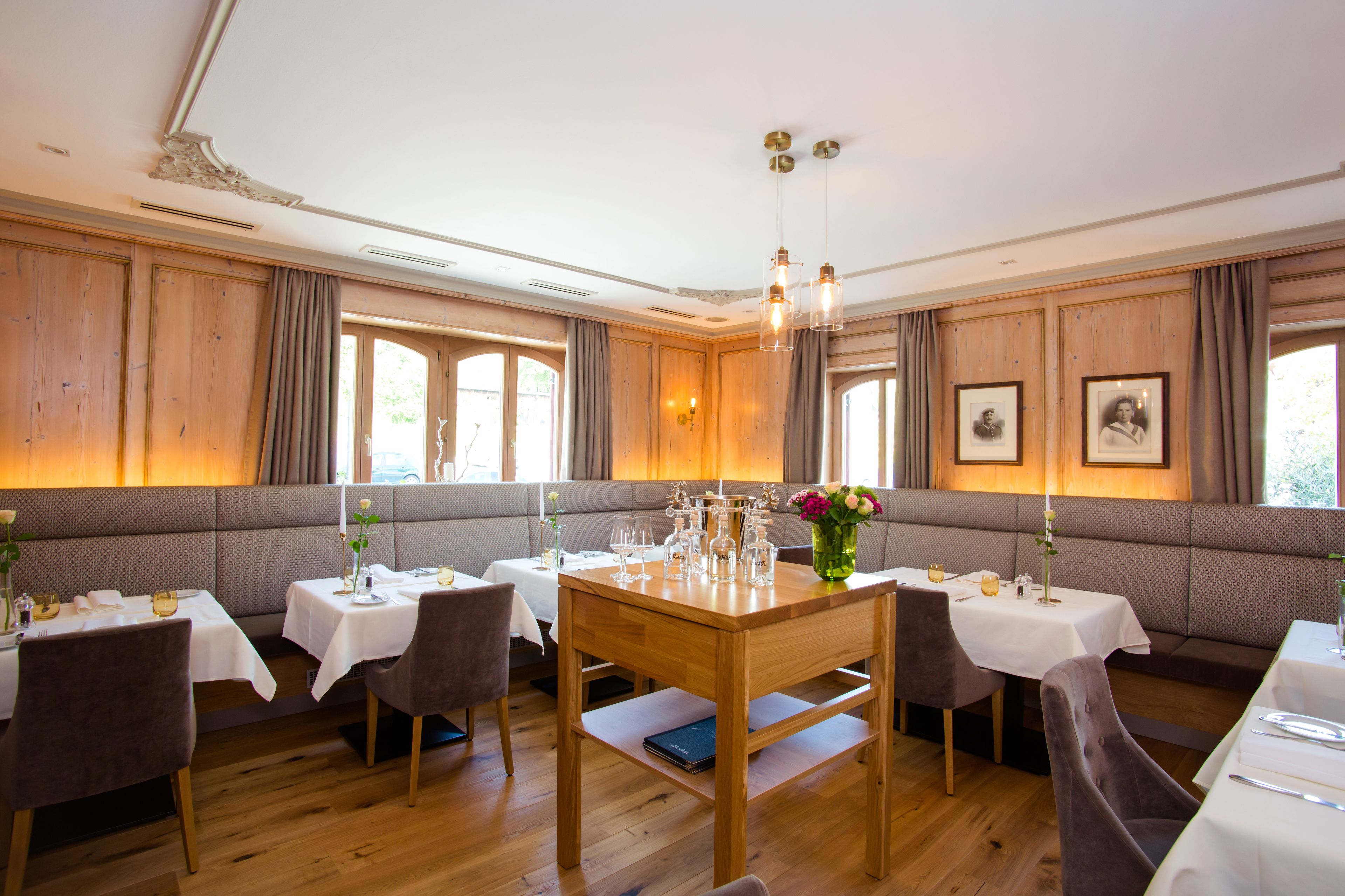 Un espace repas avec des tables en bois, des sièges rembourrés et des luminaires suspendus.