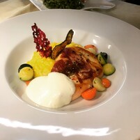 Un plato de comida con carne, verduras y una cucharada de salsa.