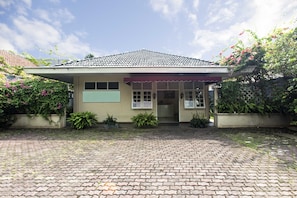 A house with a tiled roof, a covered porch, and a brick driveway.