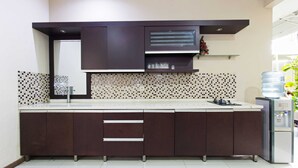 Una cocina moderna con armarios oscuros, salpicadero azulejado y dispensador de agua.
