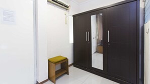 Una habitación con armario, un taburete pequeño y equipo de aire acondicionado.