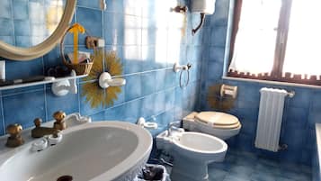 Un baño con azulejos azules, un lavamanos blanco, un inodoro y un bidé.