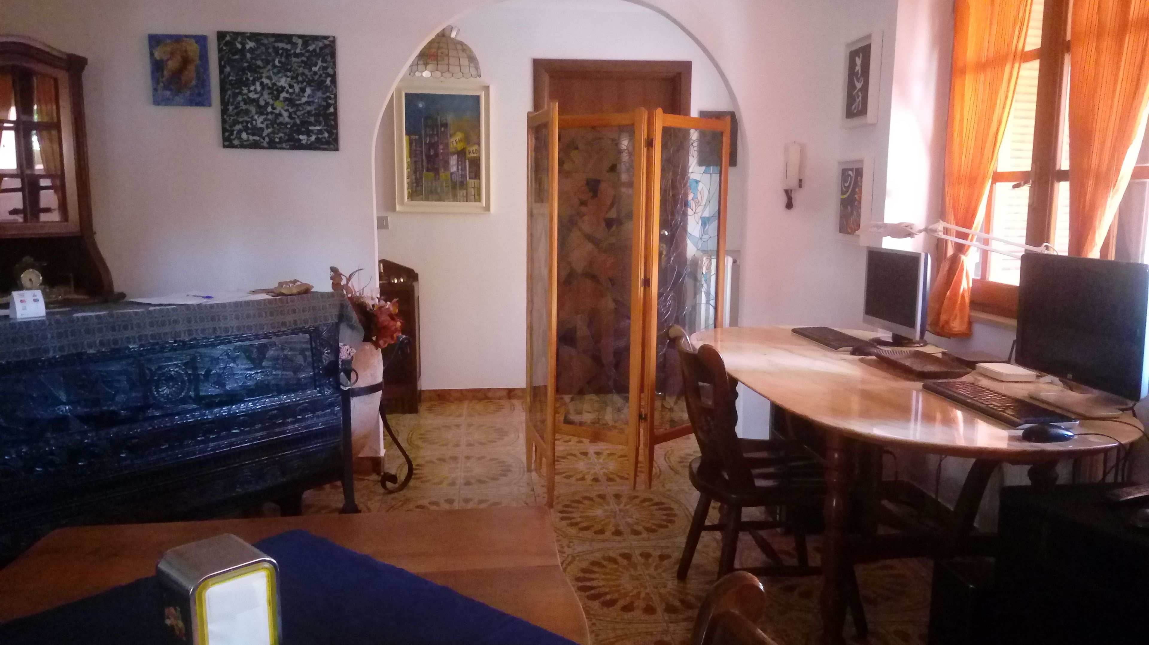 A living room with a sofa, a dining table with chairs, a fireplace, and artwork on the walls.