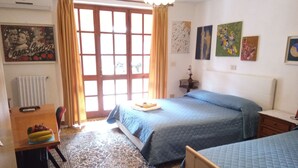 Quarto com cama, escrivaninha, cadeira e janela com cortinas.