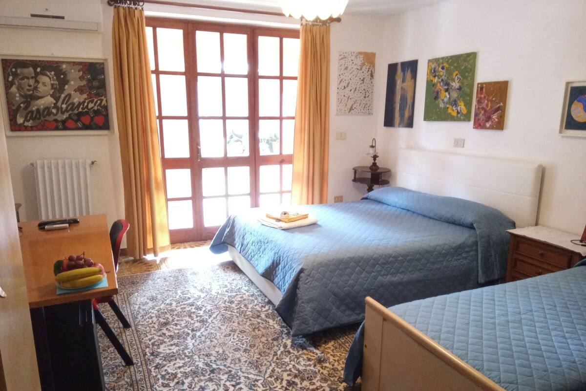 Un dormitorio con cama, escritorio, silla y ventana con cortinas.