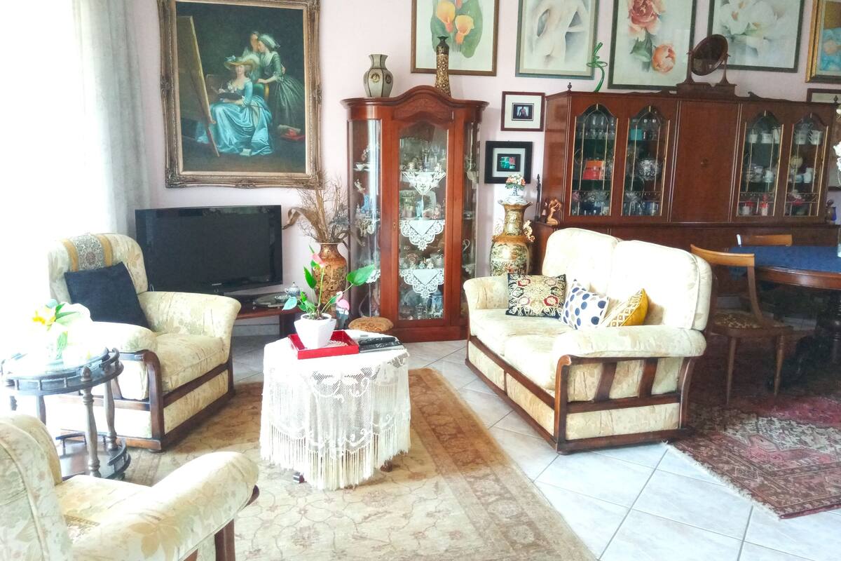 Una sala de estar con un sofá, sillones, un televisor, un mueble y un cuadro en la pared.