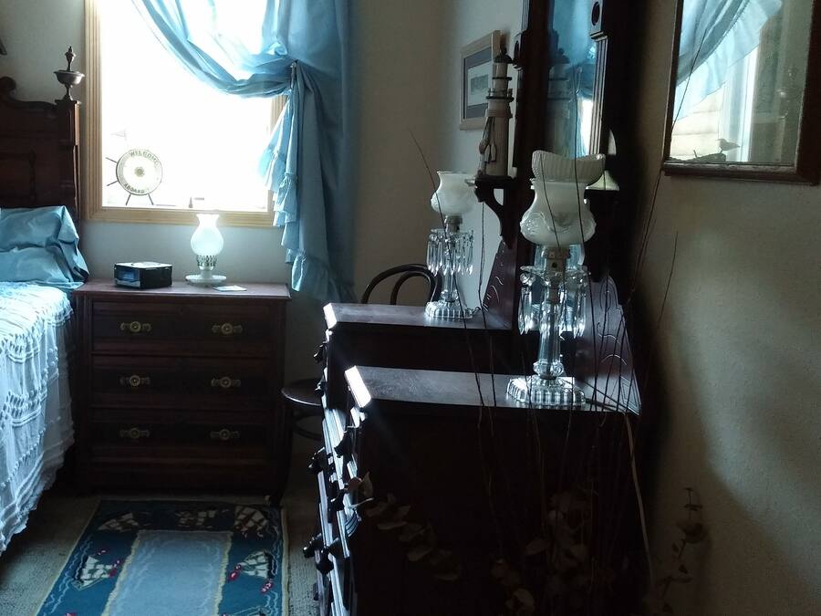 A bedroom with a bed, a nightstand, a dresser, and a mirror.