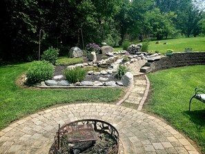 A garden with a stone pathway, a fire pit, and a pond. - Meisterhaus Bed & Breakfast (Morristown)