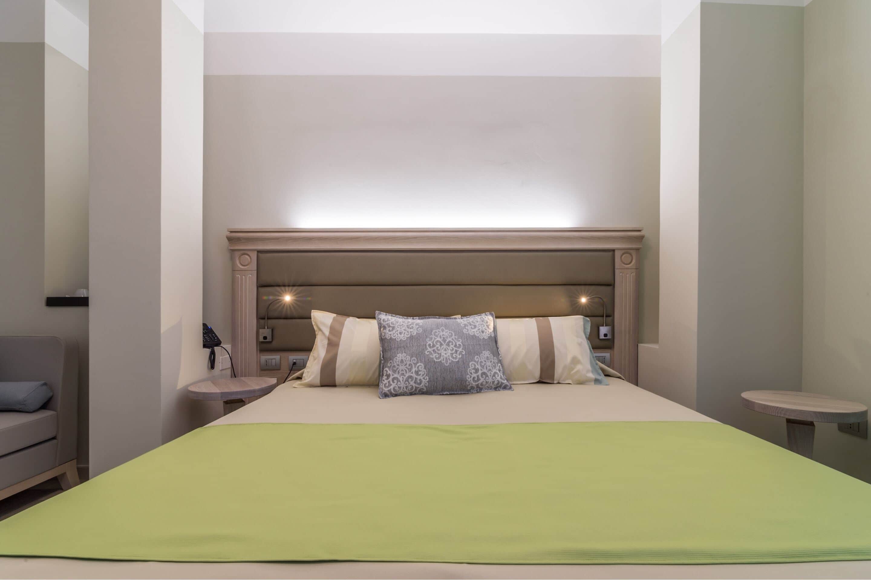 A hotel room with a large bed, a bedside table, a chair, and a small table.