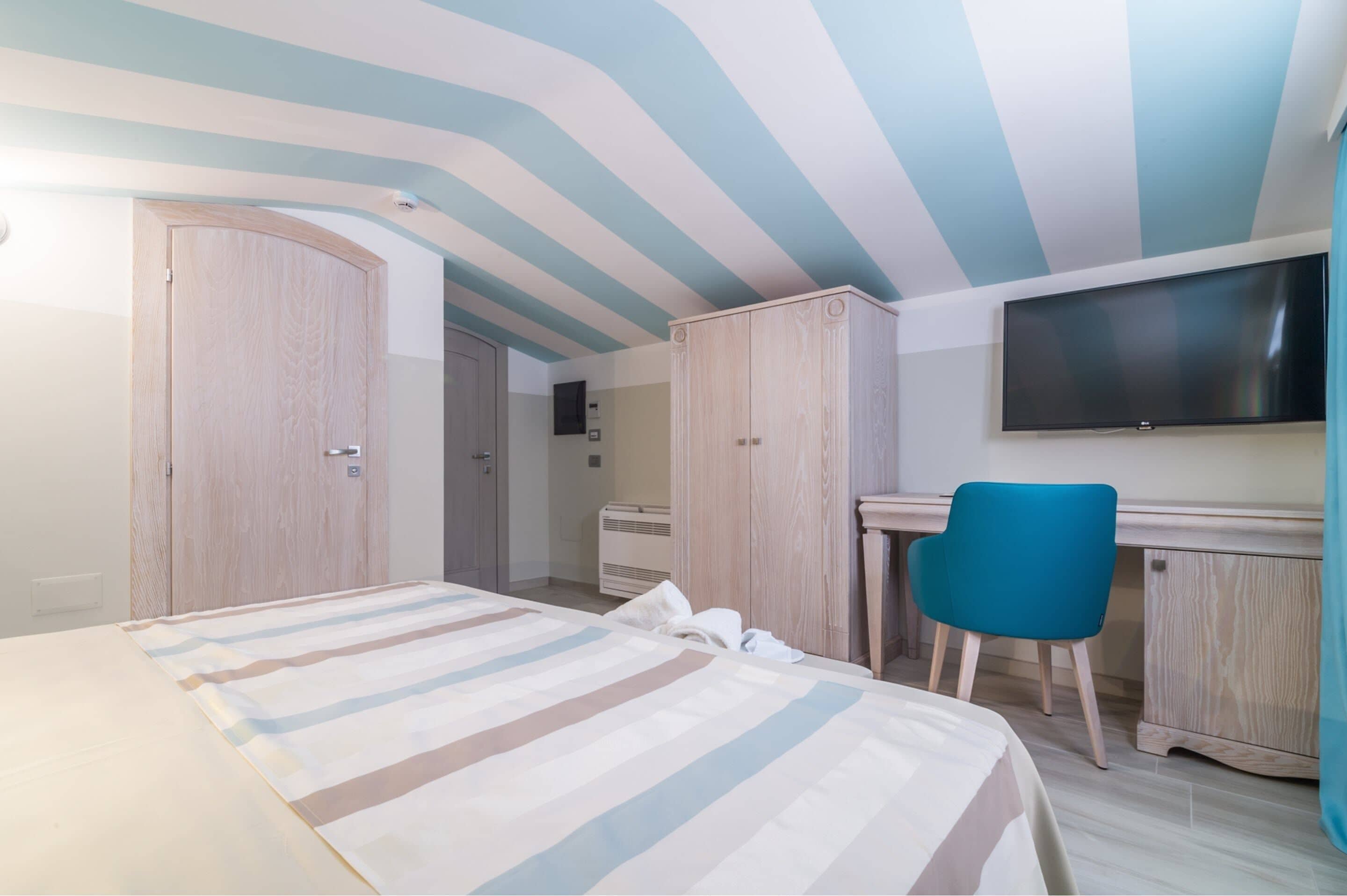 Un dormitorio con cama, escritorio, silla, televisión y armario.