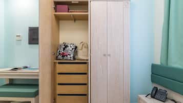 Ein Zimmer mit einem Holzschrank, einem Schreibtisch mit grünem Stuhl und einem Nachttisch mit Telefon.
