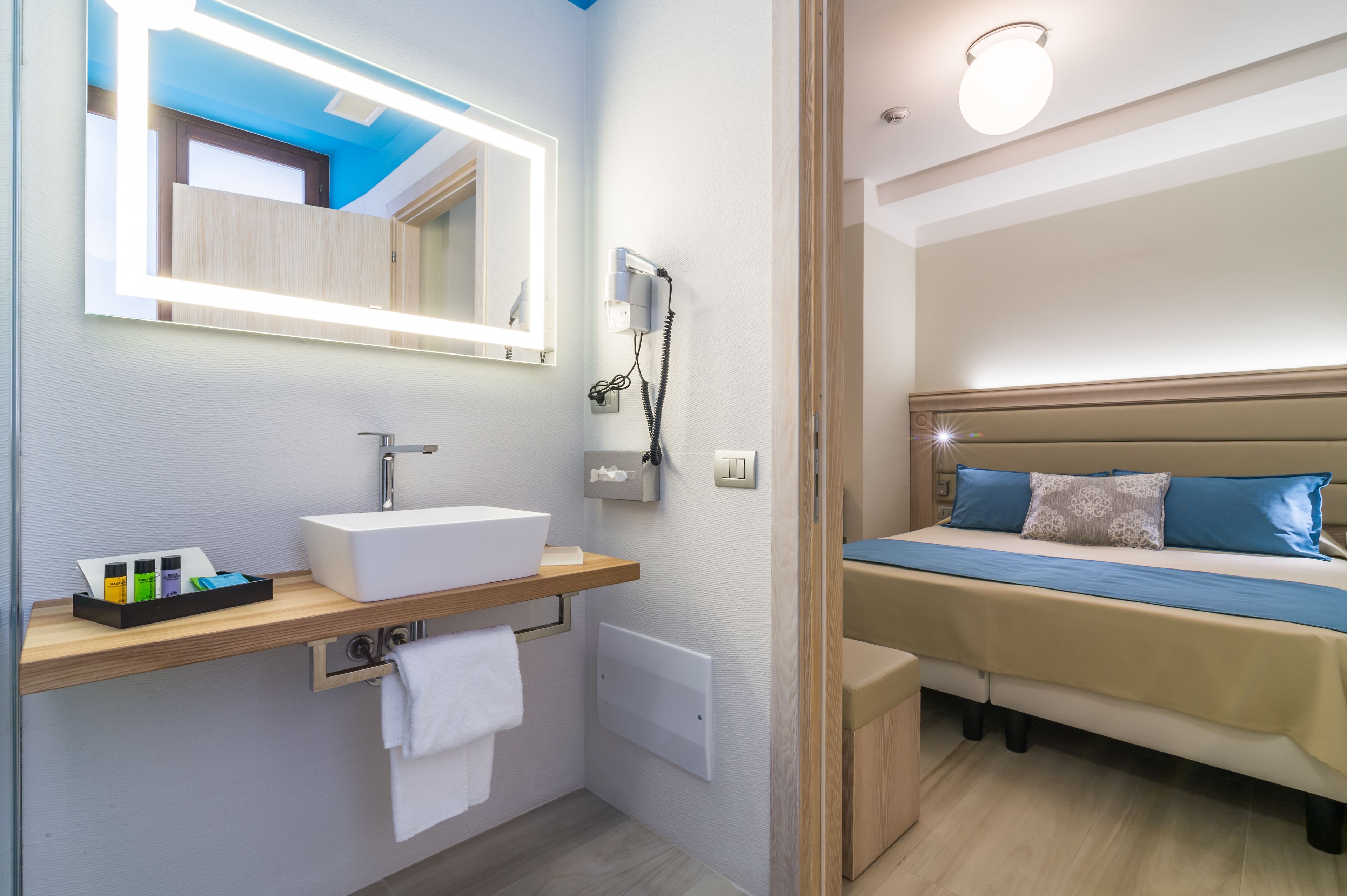 Un baño moderno con lavamanos empotrado, espejo y perchero.