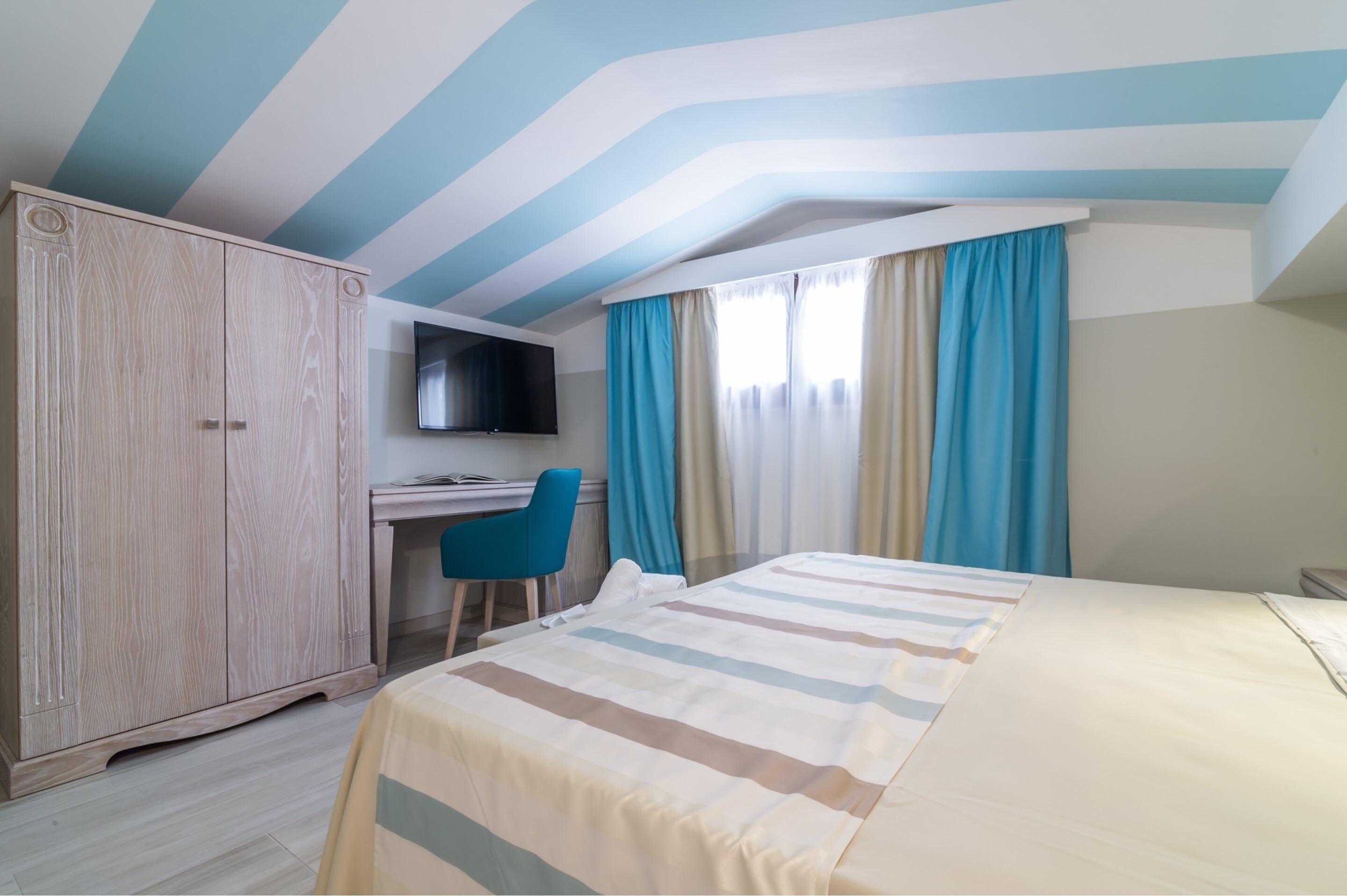 Una habitación de hotel con cama, escritorio, televisión y armario.