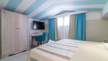 Una habitación de hotel con cama, escritorio, televisión y armario.