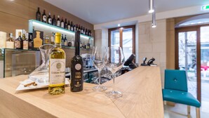 Una zona de bar con botellas de vino Chateau Simone y Festa Noria, dos copas de vino vacías y una silla azul.