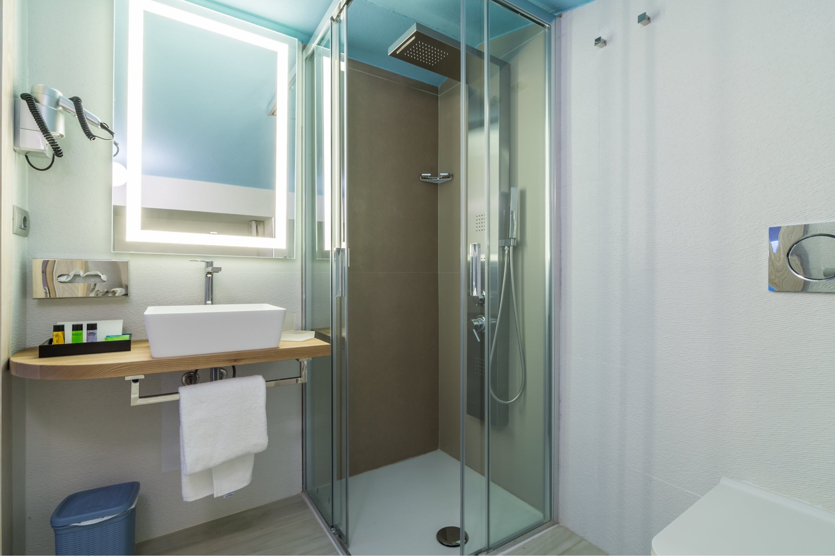 A modern bathroom with a glass-enclosed shower, a white sink, and a mirror above it.