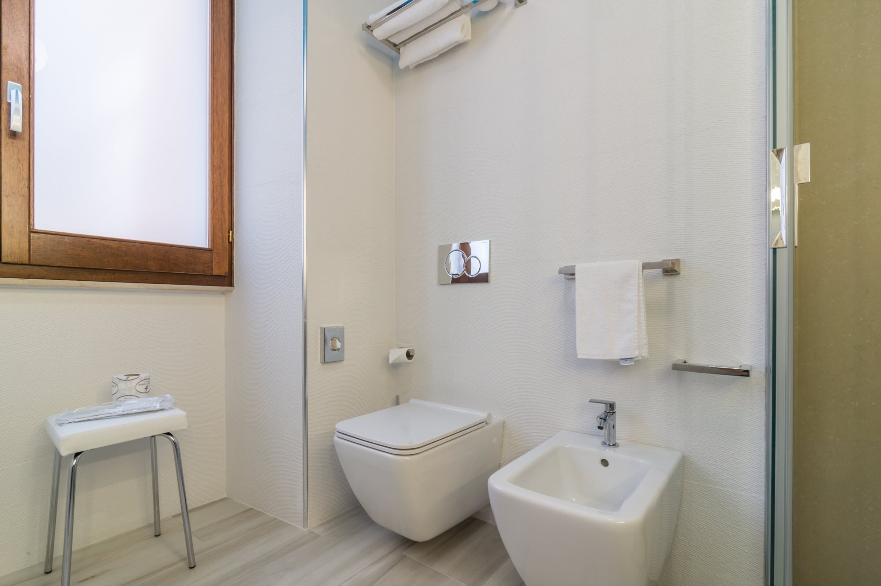 A small, clean bathroom with a toilet, bidet, and sink.