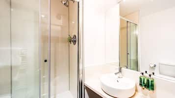 A modern bathroom with a glass-enclosed shower, a white sink, and a large mirror.