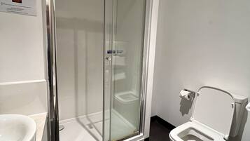 Un baño moderno con ducha envuelta en vidrio, inodoro y lavamanos.