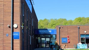 A modern building with a reception area, a sign for Riverstone Lodge & Restaurant, and a clear sky. - Riverstone Lodge Hotel (Perth)