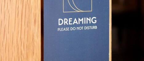 A door with a sign that reads 'DREAMING PLEASE DO NOT DISTURB' and 'RIVERSTONE LODGE & RESTAURANT' on a wooden door.