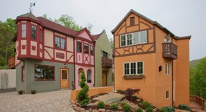 A traditional European-style building with a mix of red and yellow facades, a cobblestone driveway, and a small garden area. - Fenton Inn (Roseland)