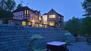 Ein traditionelles Gebäude im europäischen Stil mit einer Stein-Terrassenmauer, Außenbestuhlung und einem Whirlpool.