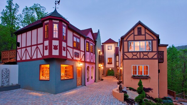 Ein traditionelles Gebäude im europäischen Stil mit roter und weißer Fassade, einem Kopfsteinpflasterhof und einer kleinen Grünanlage.