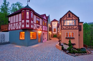 Un edificio de estilo europeo tradicional con fachada roja y blanca, un patio adoquinado y un pequeño jardín.