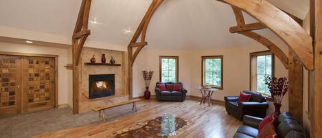 A spacious living room with a fireplace, wooden beams, a sofa, and a dining area.