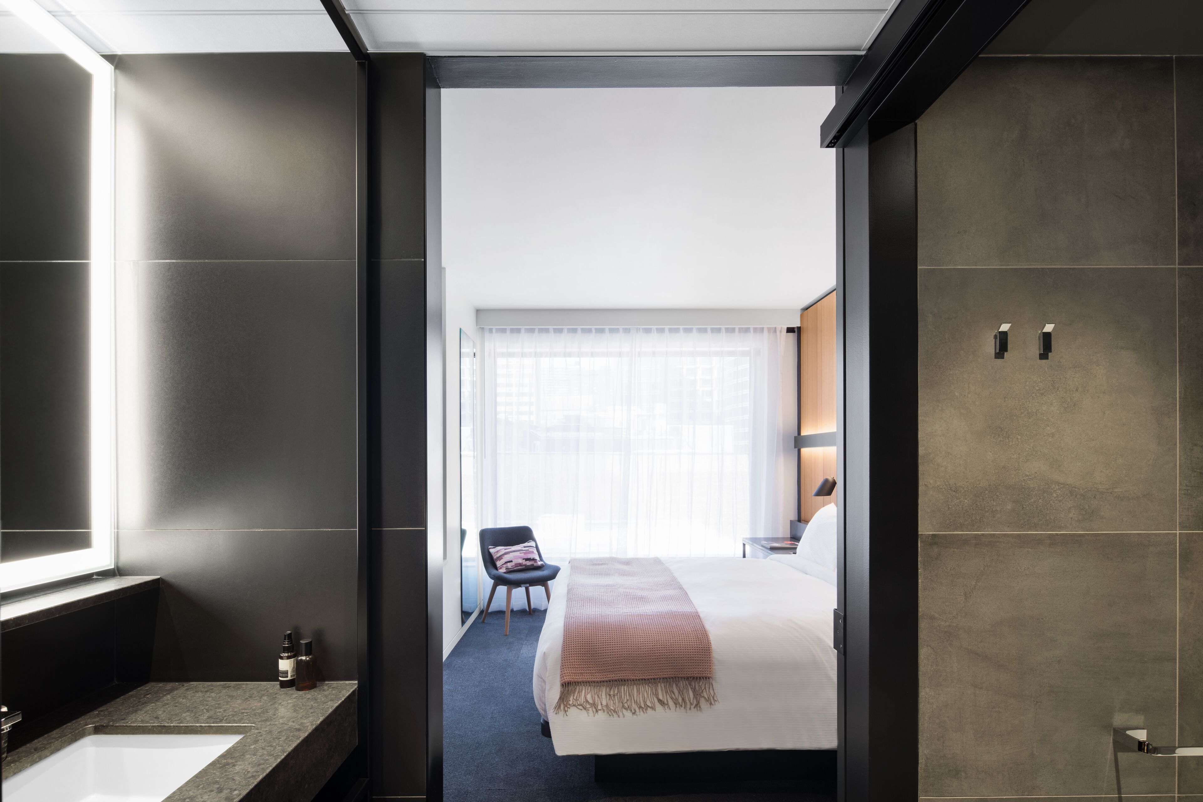Una moderna camera d'albergo con un letto grande, bagno separato e vista sulla città.