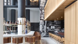 Un bar moderno con techos altos, paneles de madera y una barra larga con taburetes.