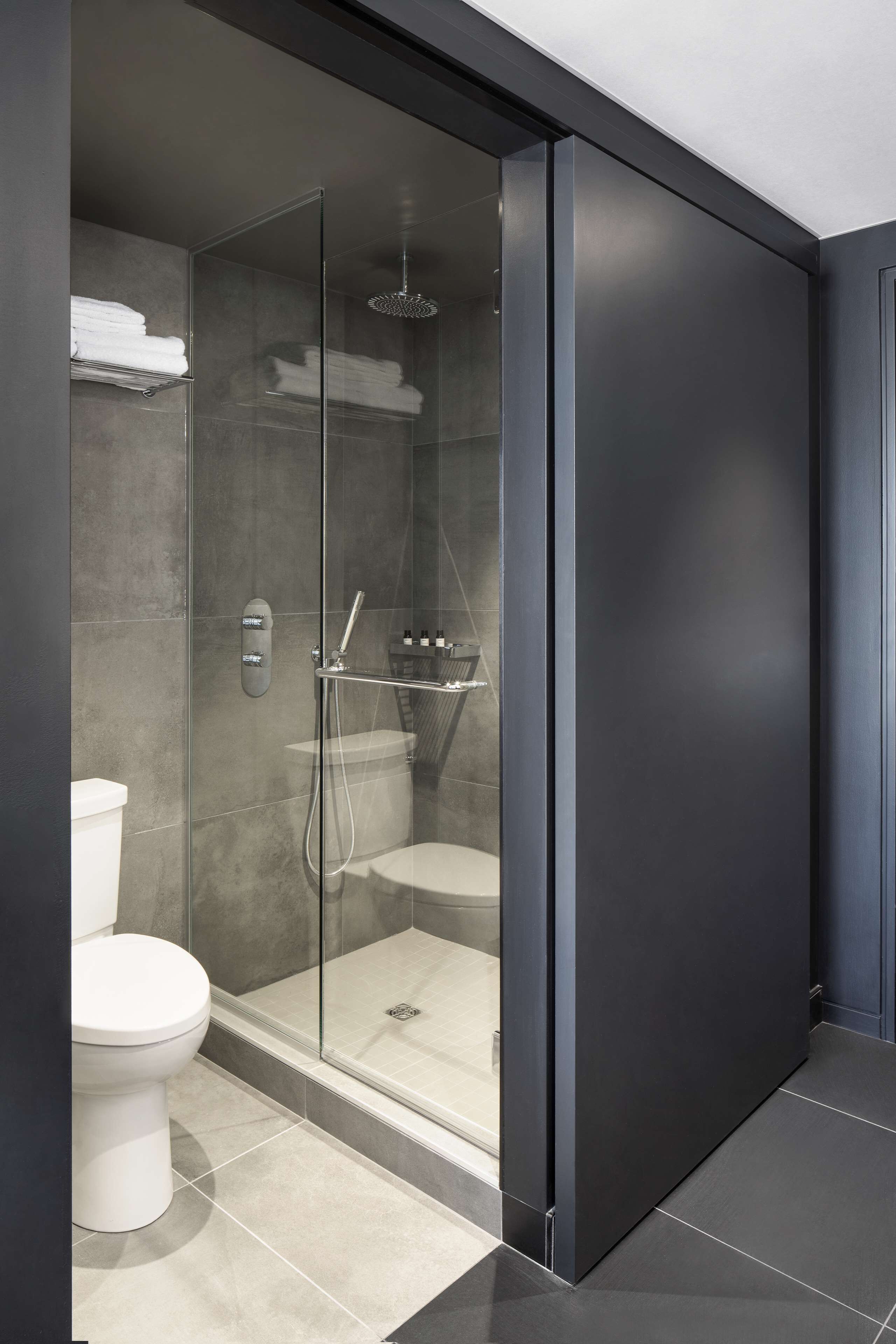 Un baño moderno con ducha de vidrio, inodoro y toallero.