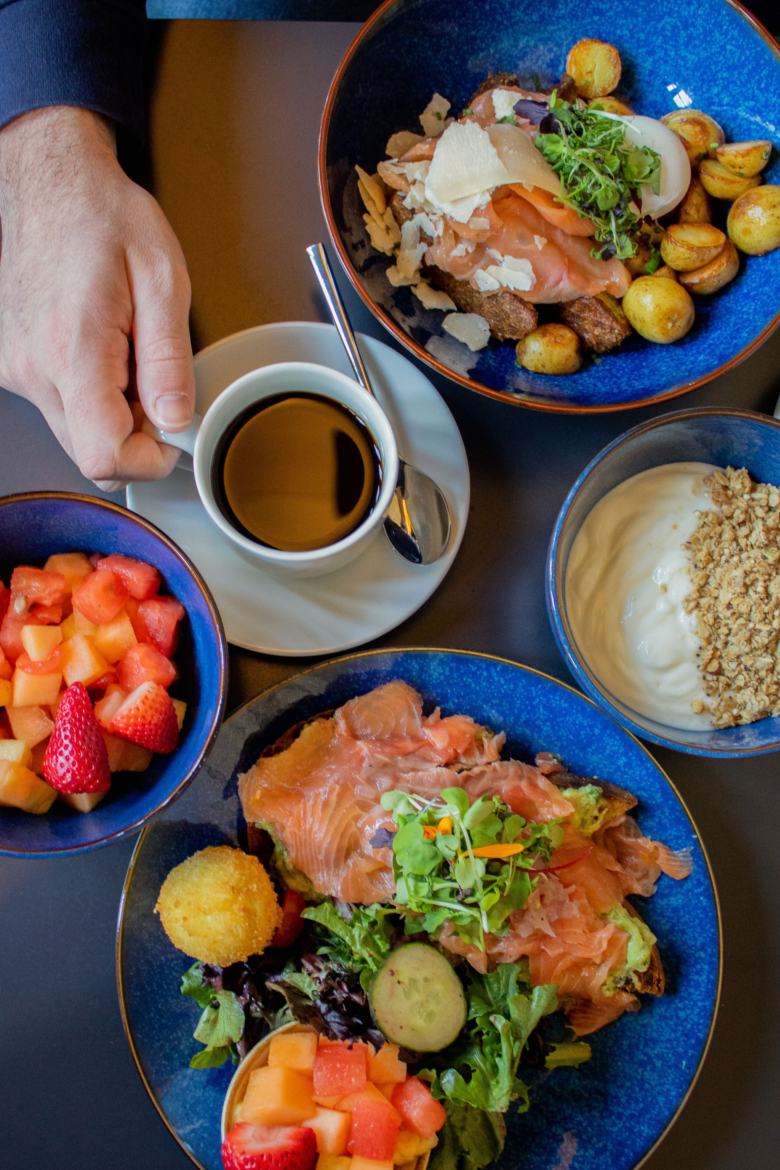 A table with various dishes including salmon, potatoes, and a bowl of strawberries.