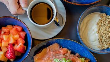 A table with various dishes including salmon, potatoes, and a bowl of strawberries.