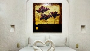 Una habitación de hotel con una cama, un arreglo de toallas con forma de corazón y un cuadro en la pared.