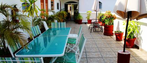 An outdoor patio with a table and chairs, surrounded by potted plants.