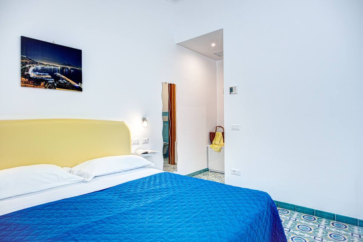 Een hotelkamer met een bed, een schilderij van het nachtzicht en een badkamer die door een open deur zichtbaar is.