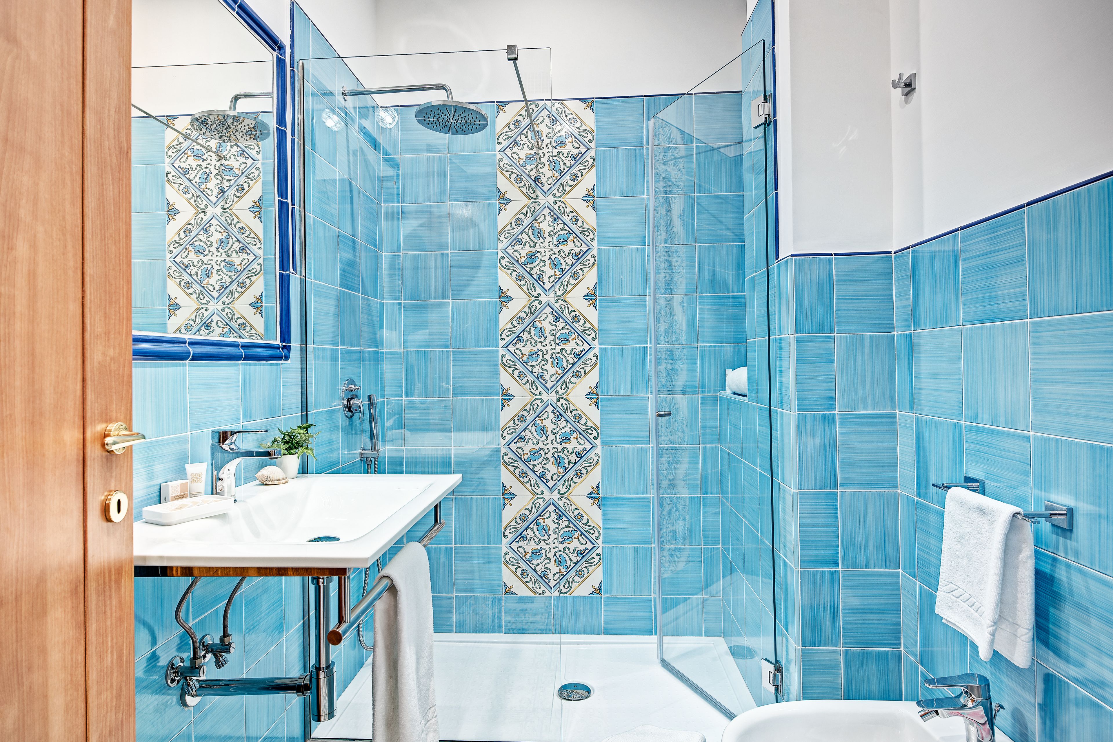 A bathroom with blue tiles, a white sink, and a shower.