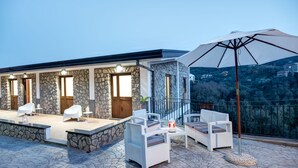 Un edificio de piedra con balcón, mobiliario exterior y vistas al paisaje.