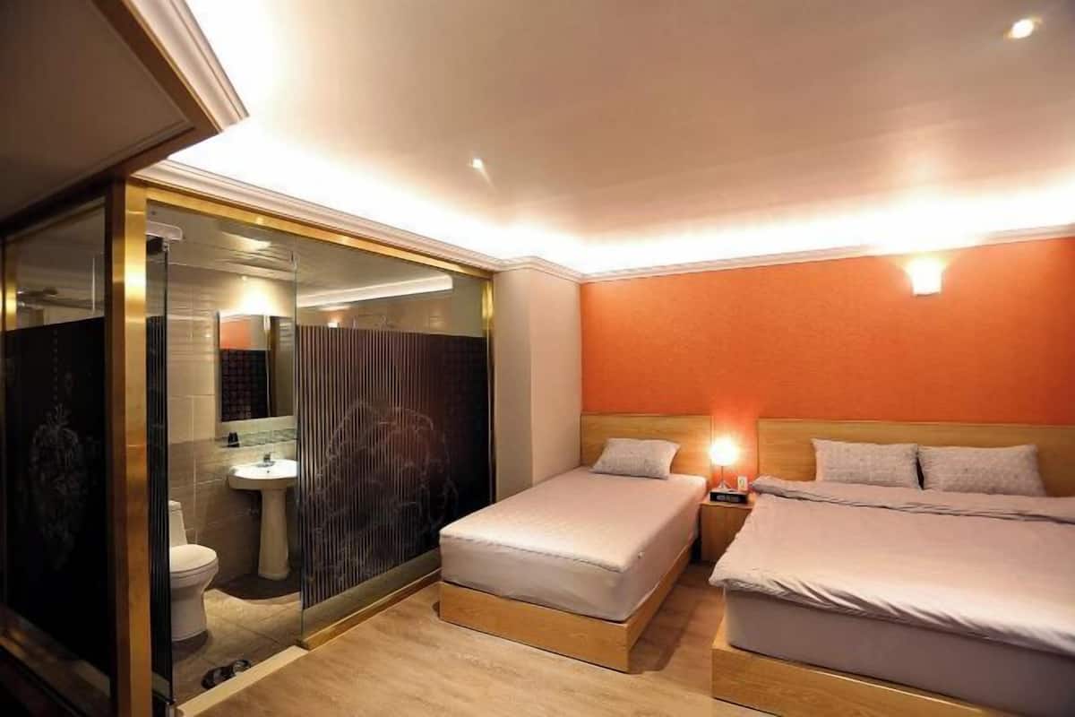 Ein Hotelzimmer mit Bett, Nachttisch und einem Badezimmer mit Toilette und Waschbecken.
