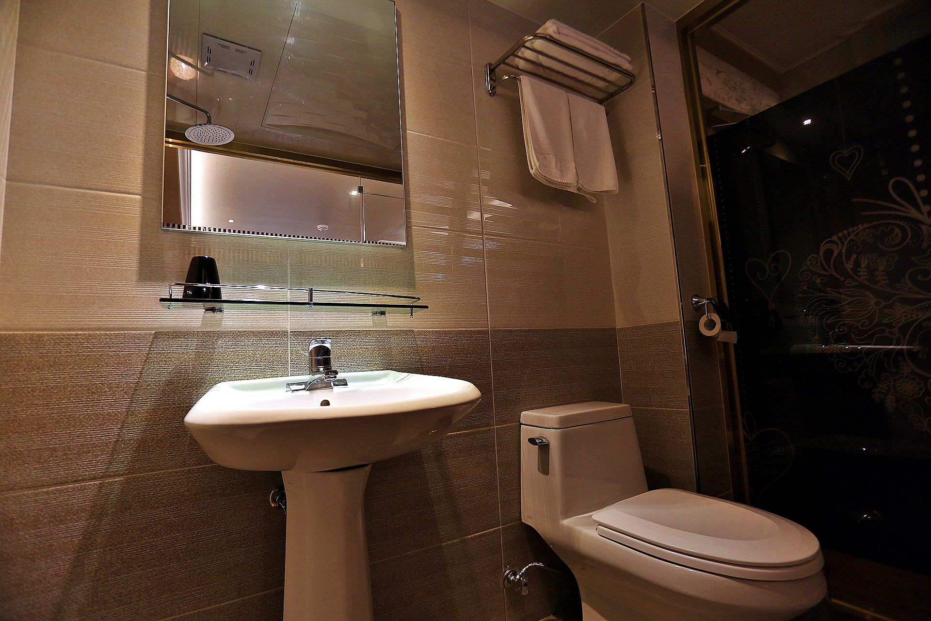 A bathroom with a sink, toilet, and a glass shower enclosure.