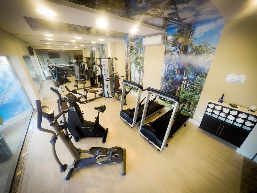 Een sportschool met diverse fitnessapparaten, een muurschildering en een receptiebalie.