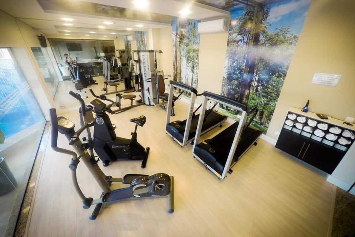 A gym with various exercise machines, a wall mural, and a reception desk.