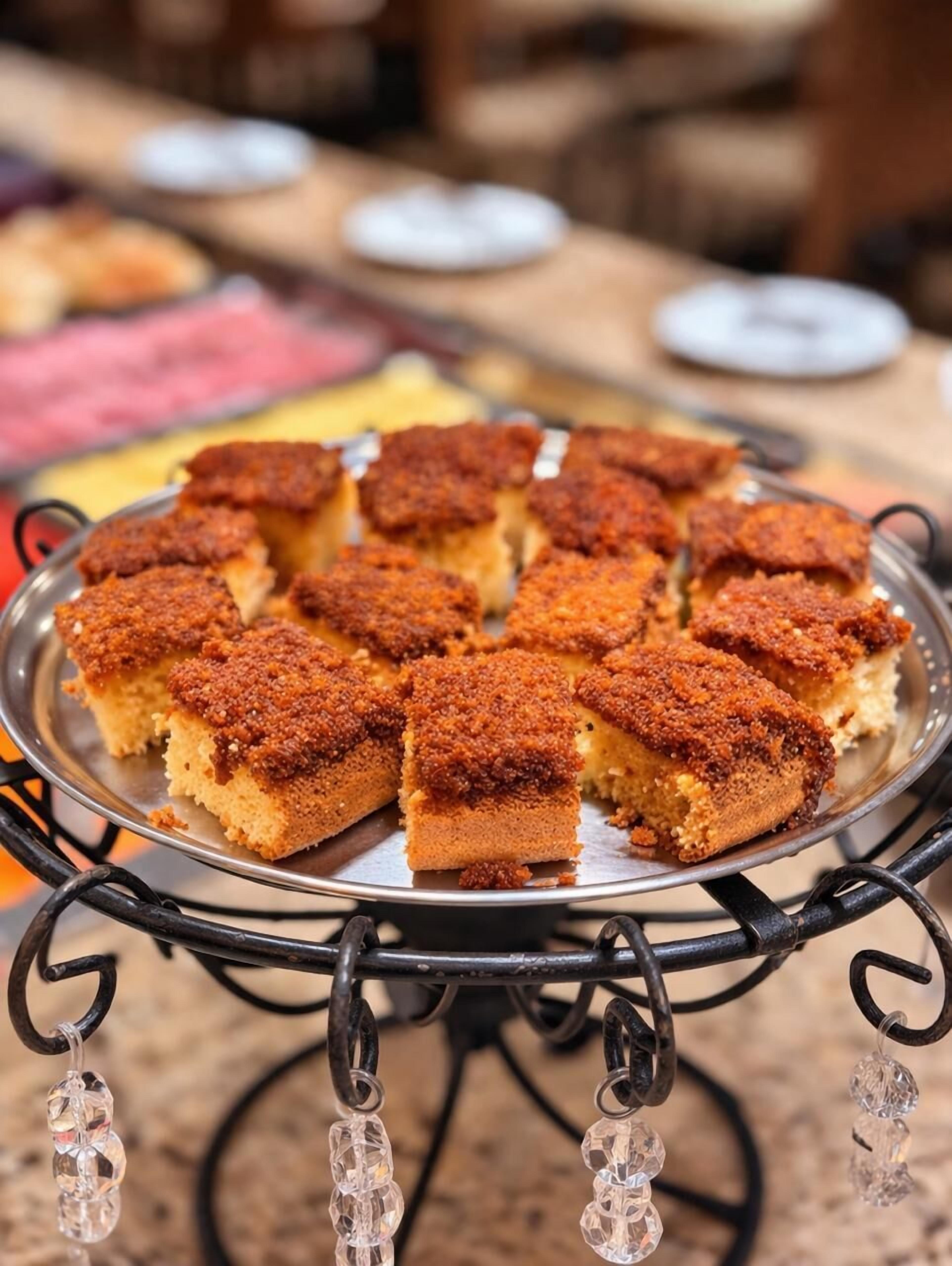 A tray of square-shaped, crumb-coated desserts on a metal stand with decorative crystal elements.