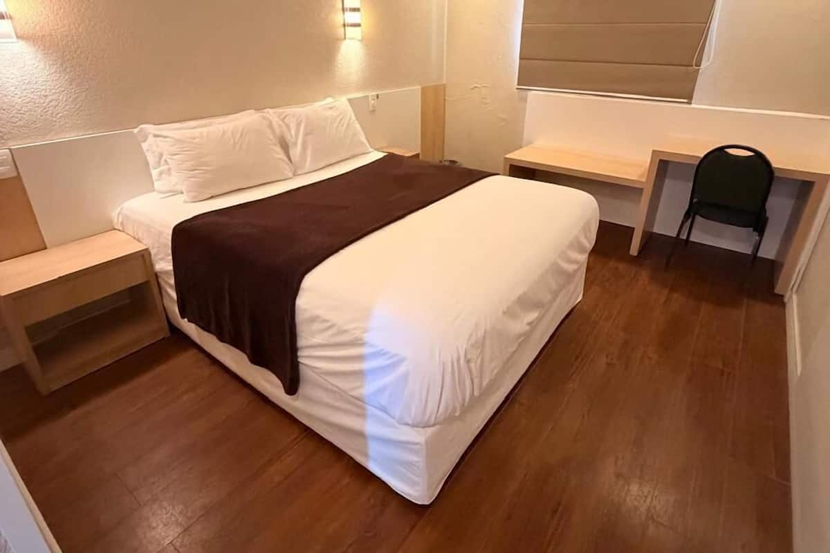 A bedroom with a bed, bedside tables, a desk, and a chair.