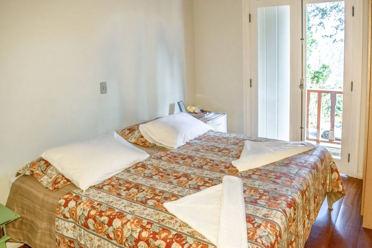 Un dormitorio con dos camas, una mesita de noche y vistas al exterior.