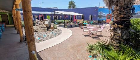 Un patio al aire libre con mesas y sillas, una estatua y un edificio con un mural.
